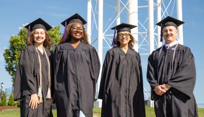 Asbury Online graduates smile in their caps and gowns.