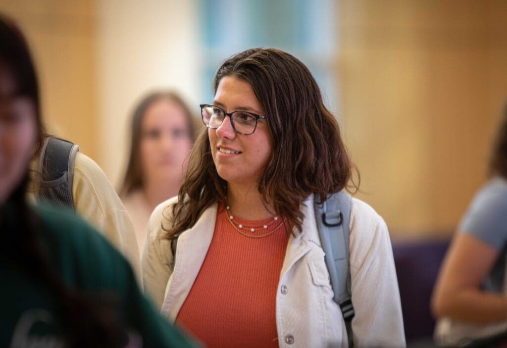 Asbury female students smiling walking in room other students.